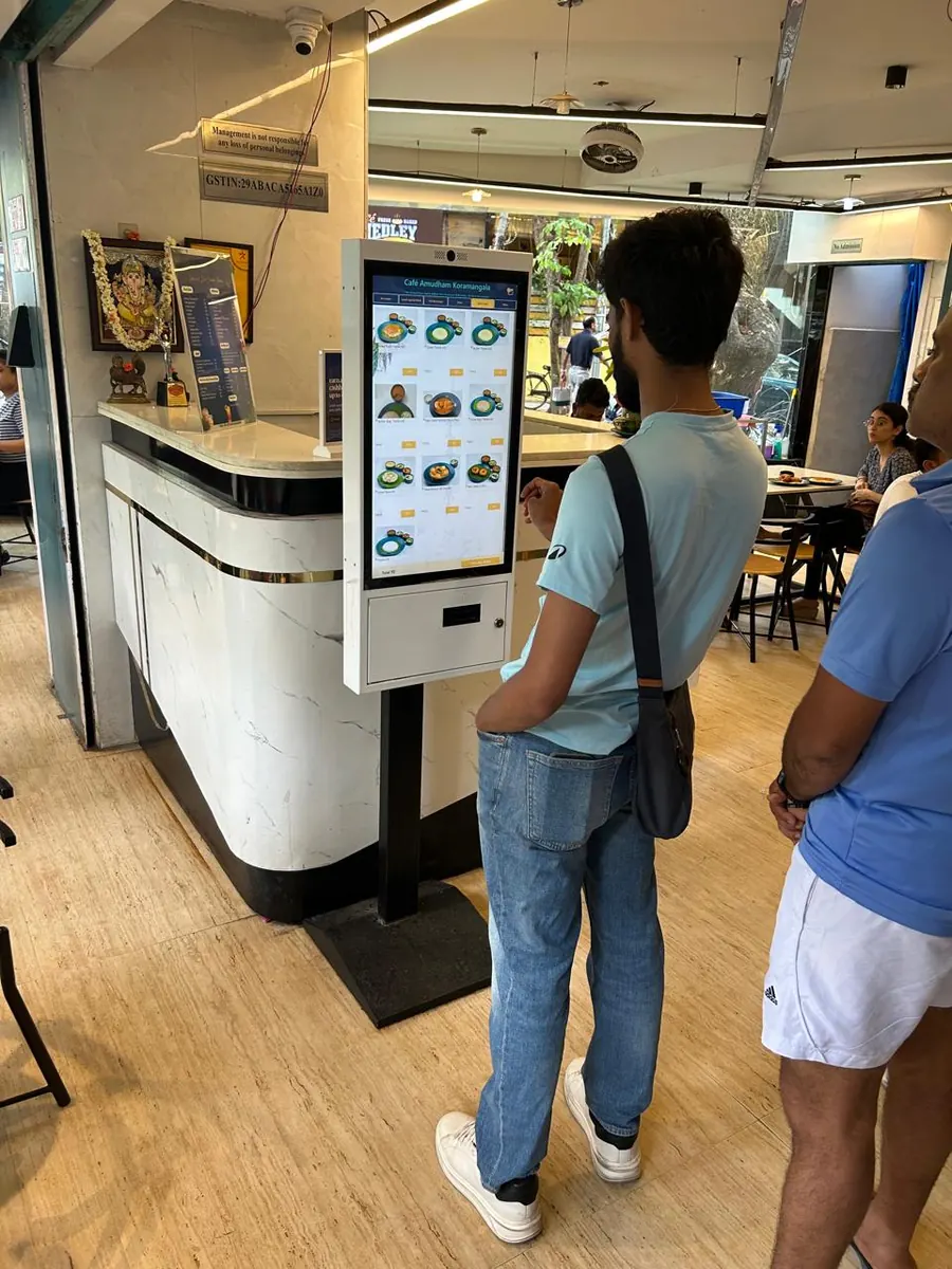 Customer using a PALAS floor-mounted kiosk in a restaurant